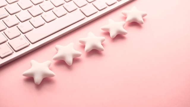 Teclado branco sobre fundo rosa com estrelas alinhadas, simbolizando avaliações e a perceção de sermos melhores que a média