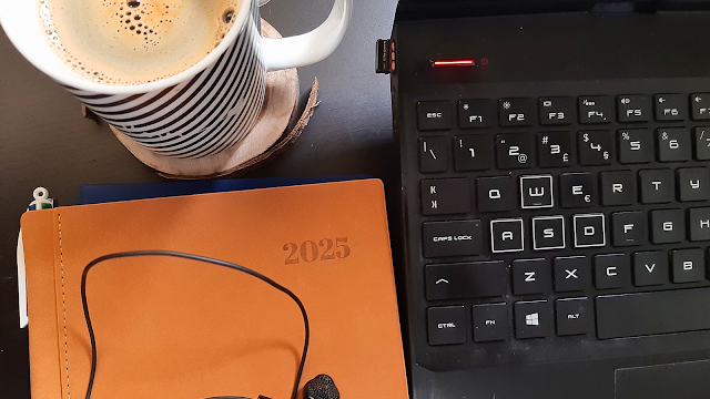 Agenda aberta ao lado de uma chávena de café e um computador, representando produtividade e organização digital.