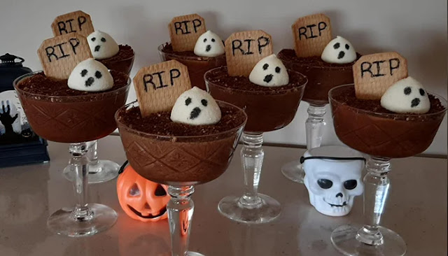 Taças de mousse de chocolate decoradas para o Halloween com bolacha “RIP” e marshmallows em forma de fantasmas.