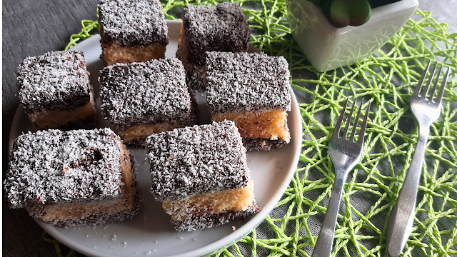 Lamingtons australianos com chocolate e coco Lamingtons tradicionais da Austrália: cubos de bolo fofo cobertos com chocolate e coco ralado, servidos num prato branco