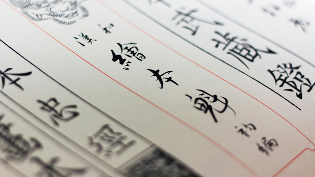 Detalhe de caracteres em caligrafia chinesa tradicional escritos a tinta preta sobre papel com linhas vermelhas, simbolizando a riqueza da língua chinesa.