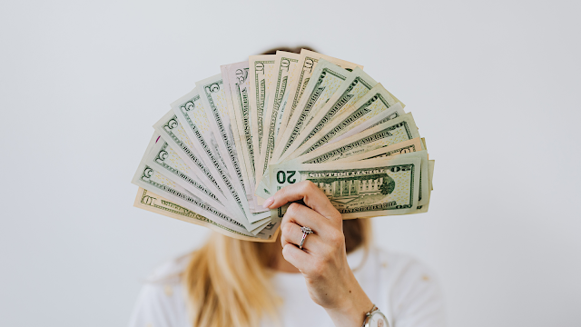 1 ano de finanças e impostos: o que aprenderam? Pessoa a segurar várias notas de dinheiro, representando controlo financeiro, poupança e gestão de finanças pessoais em Portugal