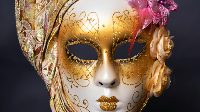 Máscara Dourada Tradicional de Carnaval Máscara de Carnaval dourada com detalhes em glitter, flores laterais e um lenço decorativo, representando a estética tradicional das celebrações carnavalescas.