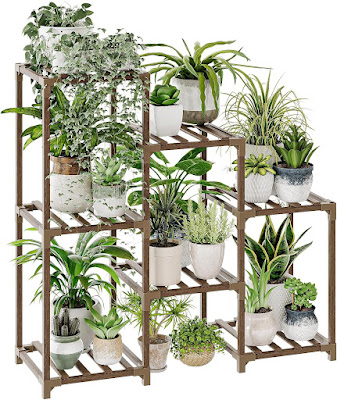 Um suporte de madeira em vários níveis, preenchido com uma grande variedade de plantas de interior e exterior em vasos decorativos de diferentes tamanhos e texturas. O móvel organiza as plantas de forma vertical, criando um visual exuberante e bem estruturado para terraços ou varandas.