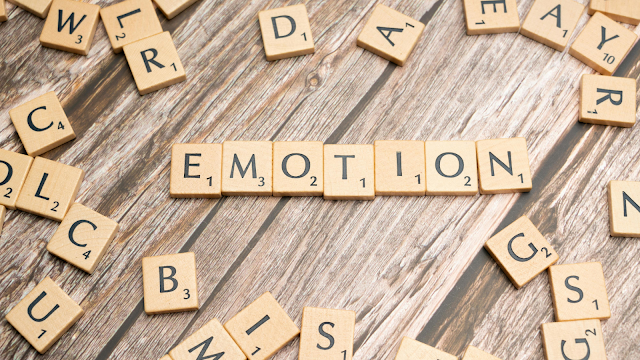 Peças de Scrabble formando a palavra “Emotion” sobre uma mesa de madeira, simbolizando o conceito de inteligência emocional e a importância de compreender as emoções.