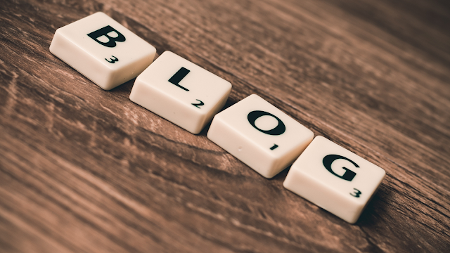 Peças de jogo formando a palavra BLOG sobre uma mesa de madeira — conceito de criação de conteúdo digital e blogging.