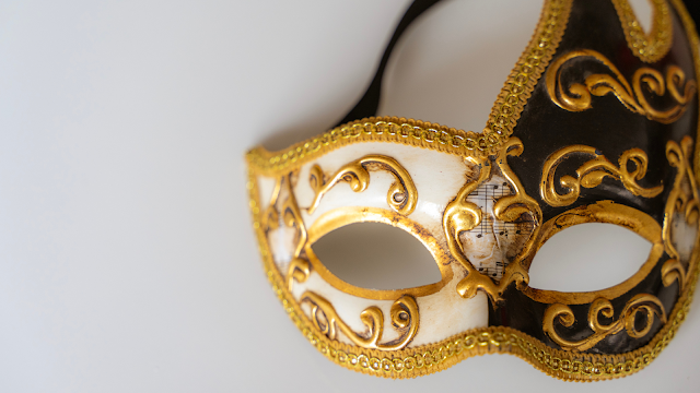 Máscara de Carnaval Elegante em Tons de Dourado Máscara de Carnaval decorativa em preto, branco e dourado, com detalhes ornamentados e padrões clássicos, fotografada sobre um fundo claro.