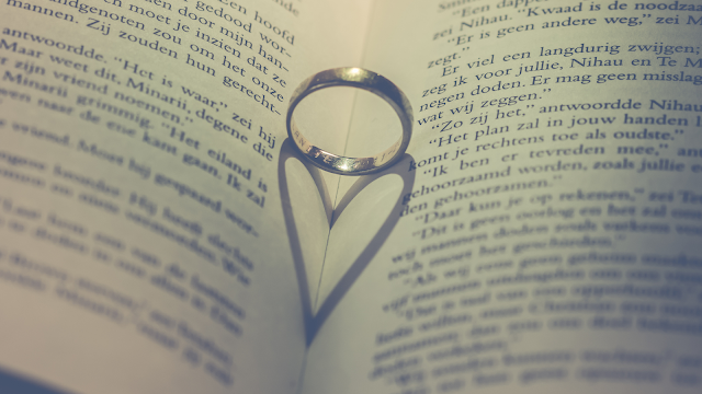 Relacionamentos devem somar, não complicar Anel pousado sobre um livro aberto formando a sombra de um coração, simbolizando amor consciente, relacionamentos saudáveis e a ideia de que o amor deve acrescentar e não complicar a vida