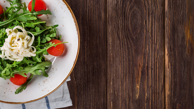 Imagem de um prato com uma salada sob uma mesa de madeira