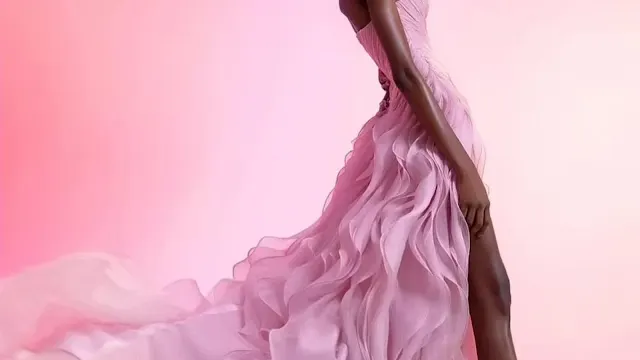 Pink Ruffled Split Prom Dress Model wearing a long, pink split prom dress with flowing ruffled layers, posing against a soft pink gradient background.